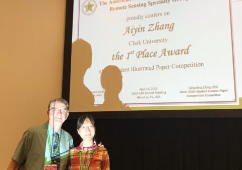Dr. Robert Gilmore Pontius and Aiyin Zhang posing in front of a screen displaying an award certificate.